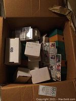 Top view of cardboard box filled with white set boxes and loose cards