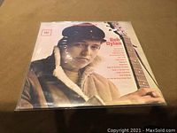 Front cover of Bob Dylan LP showcasing image of Bob Dylan with a guitar wearing a fur-lined coat and cap, with some song titles visible.