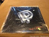 Front cover of Deep Purple Perfect Strangers vinyl album wrapped in plastic, showing prominent 'DP' logo in silver and album title in red.