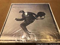 Front cover of Bryan Adams LP "Reckless" showing black and white photo of artist jumping with guitar.