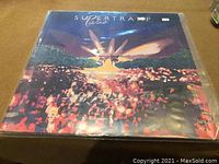 Front cover of Supertramp live LP vinyl record showing colorful stage and crowd artwork.
