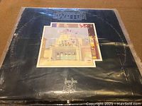 Front cover of Led Zeppelin LP album with artwork of a building and crane, in a plastic protective cover.