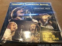 Front cover of Creedence Clearwater Revival Greatest Hits 3 LP box set showing the band photos and collection text.