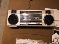 Front view of Sanyo boom box showing dual speakers, cassette player with cassette inside, and high-speed dubbing label.