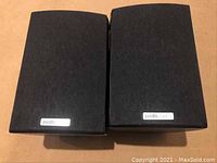 Front view of two Polk Audio RM 101 bookshelf speakers with fabric grilles on.