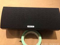 Front view of the speaker with fabric grille attached and Polk Audio logo center bottom.