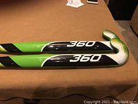 Two green and black 360 field hockey sticks side-by-side showing curved hook head with visible 360 branding