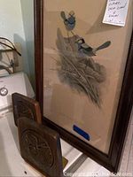 Photo showing wooden American eagle bookends with brass embossed seal in front of framed bird picture in glass.