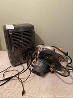 Ryobi circular saw and Utilitech portable heater positioned on carpeted floor, with cords visible