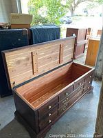 Photo of open Ethan Allen cedar chest showing the interior and exterior, including brass hardware, wood grain, and scratches