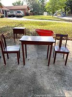 Full view of folding table set with two chairs and a small end table outdoors on driveway