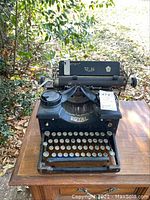 Front view of the vintage Royal typewriter on a wooden table outdoors, showing the entire machine with keyboard and carriage.