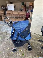 Side profile of blue stroller showing fabric canopy, black frame, and wheels.
