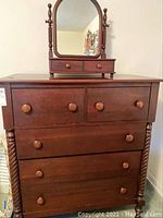 Front view of tall dresser with five drawers and matching attached mirror. Shows round knobs and twisted side columns.