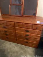 Front view of the wooden double dresser with six drawers and mirror on top.