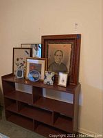 Wood shelf with vintage framed photograph and smaller framed prints on top, showing overall setup and condition.