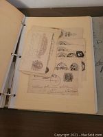 Open binder showing a page with eight postal cards featuring preprinted stamps and handwritten addresses.