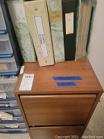 Top and front view of file cabinet showing medium brown finish, surface scratches on top, two drawers and matchbook binders on top