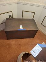 Front angled view of the wooden chest showing top and side surfaces, the chest lid closed.