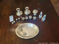 Photo of full lot showing all items arranged on table: 4 sets of salt and pepper shakers, 2 candle holders, 2 small bowls with spoons, oval platter, covered dish.