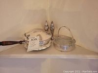 Photo showing the silver plate salt and pepper shakers, silver plate basket with glass insert and handle, and silver plate covered pan with wooden handle.