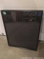 Full view of a rectangular shadow box with a glass front and black frame, showing some scratches on the glass.