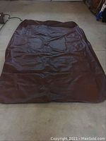 Brown pool table cover spread on a floor showing size and material texture