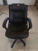 Front view of black office chair showing padded cushioned seat, backrest and armrests, and caster wheels.