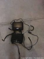 Two Sylvania DVD players laid out on floor with visible straps, controls, and cables.