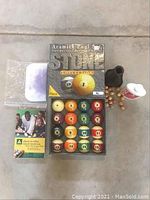 Full set of Aramith Stone Collection pool balls in box with billiard tips, scratch remover, and other accessories visible