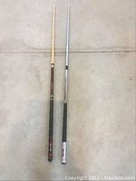 Full length front view of two pool cues, showing the complete shafts and butts.