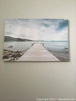 Front view of canvas art print showing dock and water under cloudy sky.