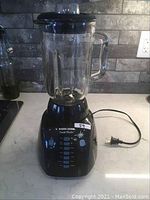 Black & Decker Crush Master blender on a kitchen counter showing front control panel, glass pitcher, power cord.