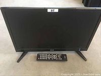 Front view of the RCA 18.5 inch LCD TV with the remote control placed in front of it on the floor.