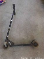 Full view of the kids scooter showing black frame, handlebar, and yellow wheels on a concrete floor.