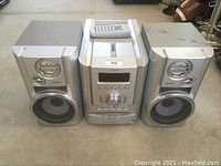 Front view of Sony stereo system with central unit flanked by two speakers and remote on top of central unit