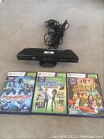 Xbox 360 Kinect sensor with power adapter and three Kinect game cases laid out on a surface.