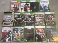 Full view of 14 Xbox 360 game cases arranged in rows on the floor, showing covers for each game.