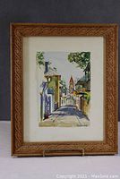 Front view of framed watercolor showing street scene.
