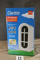 Front view of the sealed box showing the Claritin air purifier product with claims of up to 99.97% airborne allergen removal and permanent true HEPA filtration.