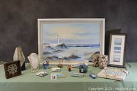 Full view of all lot items arranged on table with seascape painting in back