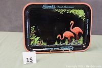 Full view of rectangular vintage metal tray with pink flamingos, green foliage, and orange rim. Shows the branding and design on the front.