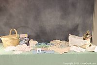 Wide view of two baskets filled with various vintage crochet and needlework pieces including doilies and a book.