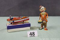 Mechanical wind-up clown and Felix the Cat in boat toys displayed together, showing size and condition.