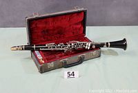 Full view of the clarinet inside the open case showing the clarinet, its mouthpiece, and the red velvet lined case interior.