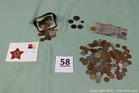 Overview of lot showing various loose coins spread across surface, a worn Mexican bill, a small black coin purse, and the Russian Ruble First Day card with red star and stamp