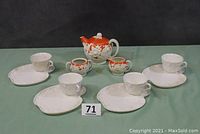Full tea set with teapot, cream, sugar bowl, four cups and four plates arranged on table