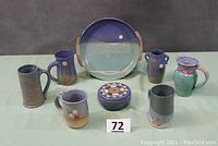 Group shot showing all eight art pottery pieces on green backdrop
