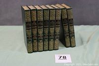 Photo of the full set of eight green hardcover volumes standing upright, edges slightly worn.