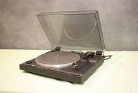 Side angle showing the dust cover open, the platter, and tonearm, illustrating overall condition and completeness of the turntable.
